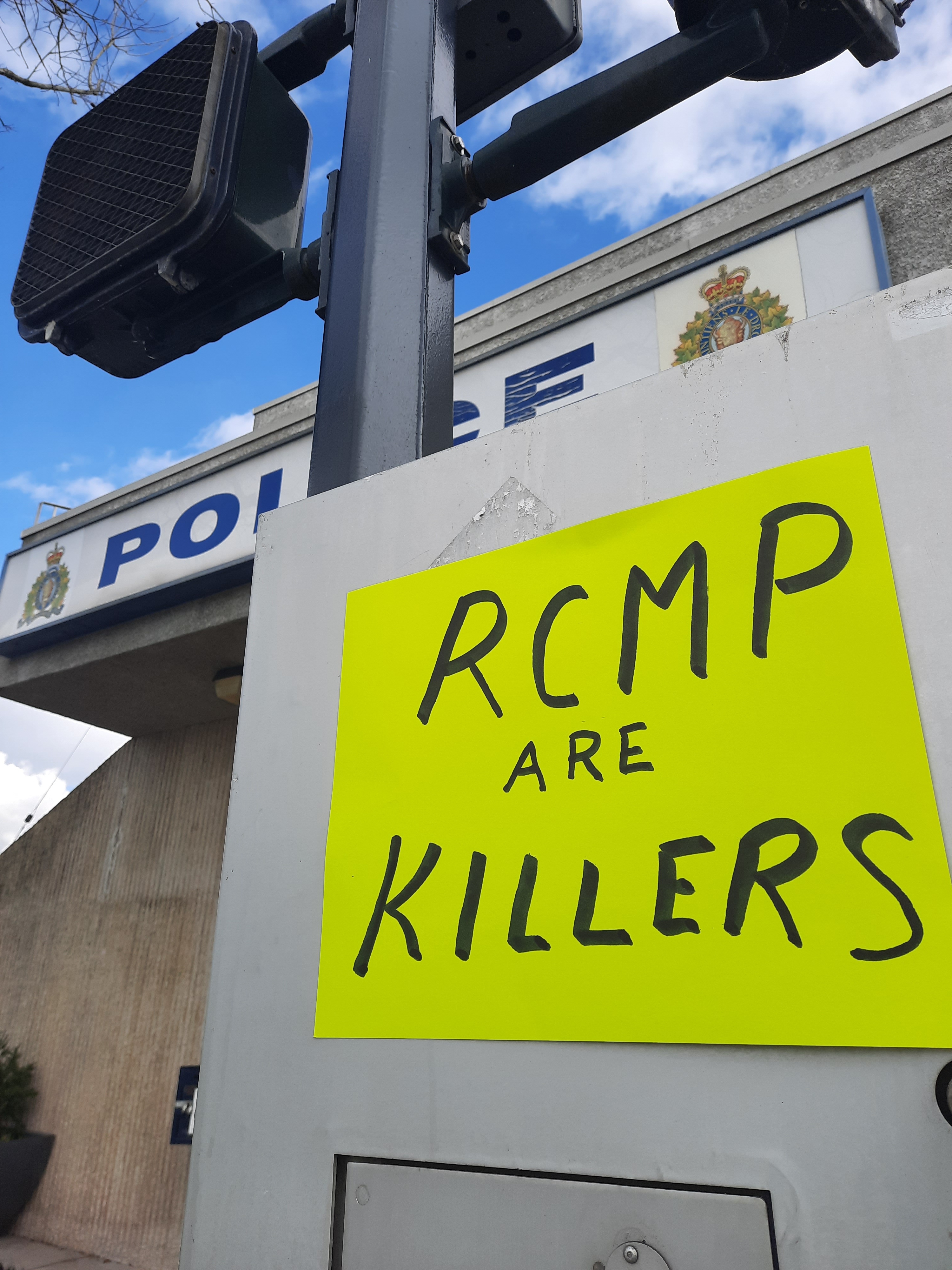Poster saying RCMP Are Killers, on a post in front of an RCMP detachment.