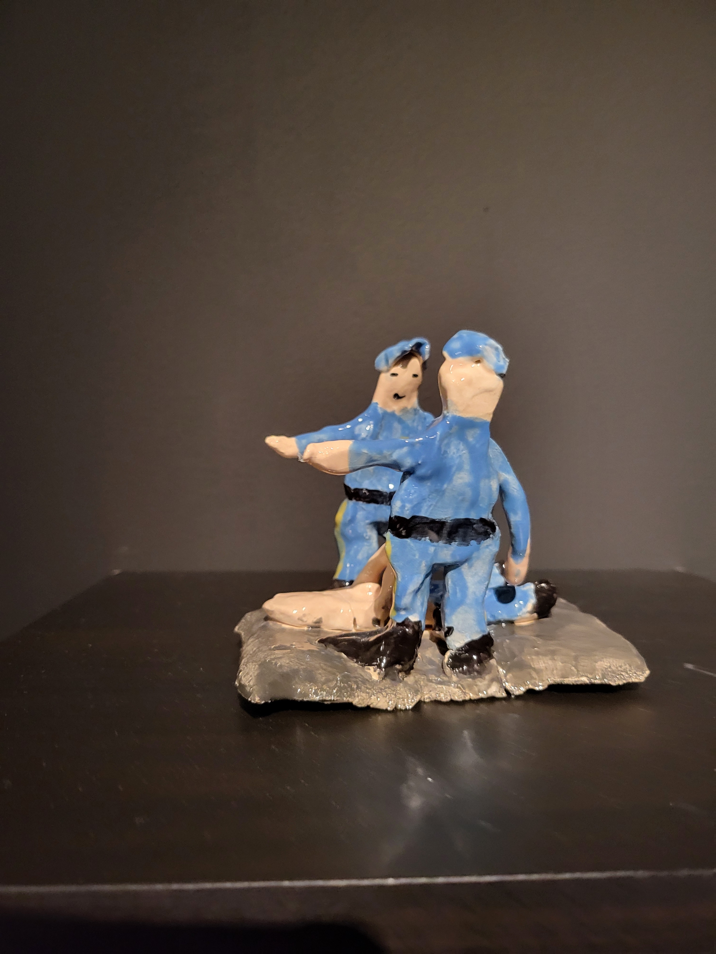 Two cops standing over person on ground sculture.