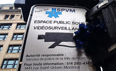 "Fuck the" graffiti on Montreal police surveillance sign.