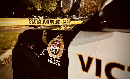 Front of a Victoria Police car at night with caution tape in the background.